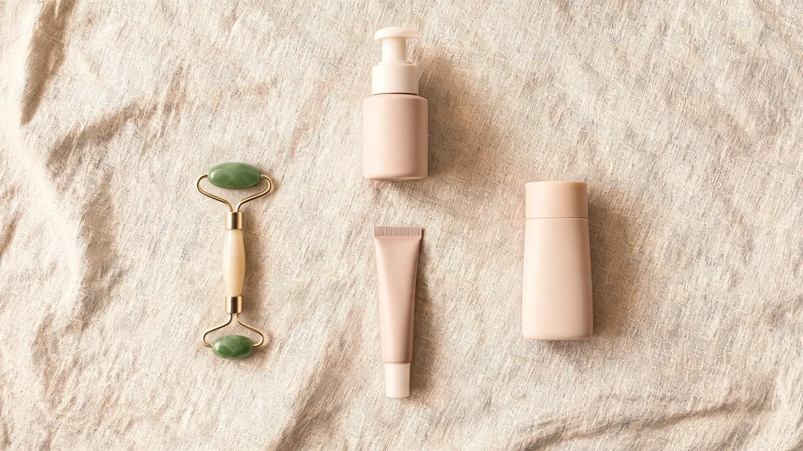 Overhead flat-lay of a skincare shelf showing the RoC eye cream tube alongside a mineral sunscreen, a gentle cleanser, and a jade roller, arranged neatly on a warm linen surface
