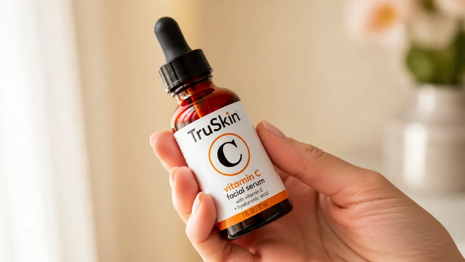 TruSkin Vitamin C Serum bottle held in a woman's hand against a cream-colored background