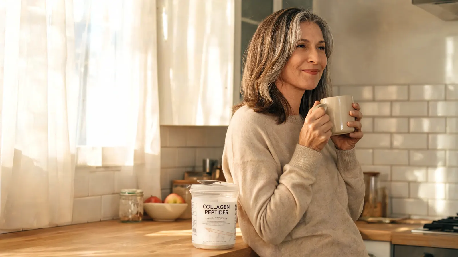 Woman in her fifties holding a mug of coffee with collagen powder on the counter beside her